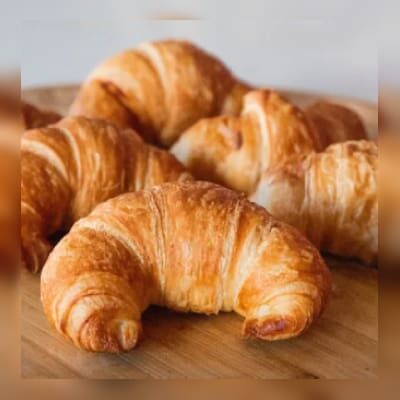 Golden, flaky croissants on a wooden surface.