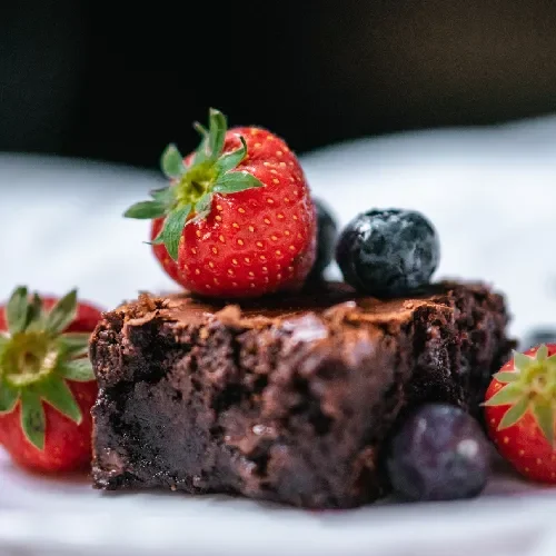 Rich chocolate brownie topped with fresh strawberries and blueberries.