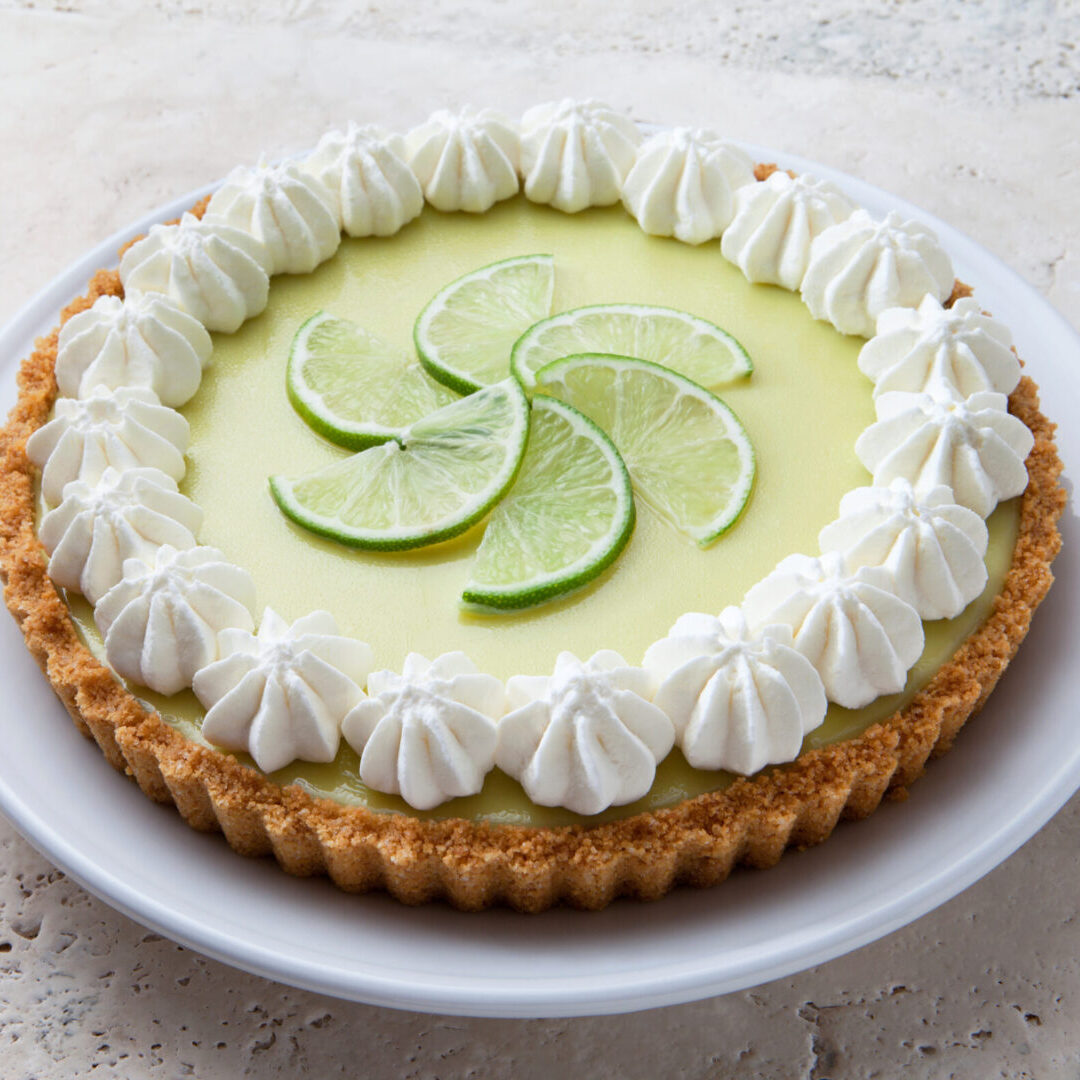 A creamy key lime pie garnished with lime slices and whipped cream.